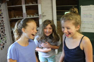 Three girls laughing in a cabin at a summer camp for neurodivergent children