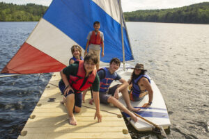 A group of children on a dock after a sailboating lesson at Camp Akeela, a summer camp for neurodivergent children, located in Vermont.