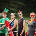 Counselors lined up in superhero costumes outside a cabin, ready to lead a themed all-camp event at Camp Akeela in Vermont